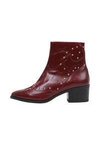 Bottines en cuir rouge avec un bout pointu, ornées de clous en argent et d'un motif décoratif sur le côté, dotées d'un talon épais.