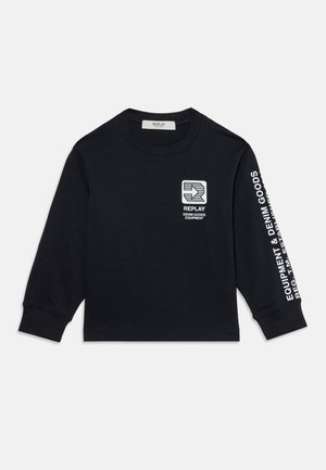 Chemise noire à manches longues avec logo blanc "REPLAY Denim Goods Equipment" sur la poitrine et texte blanc sur la manche droite sur fond uni.