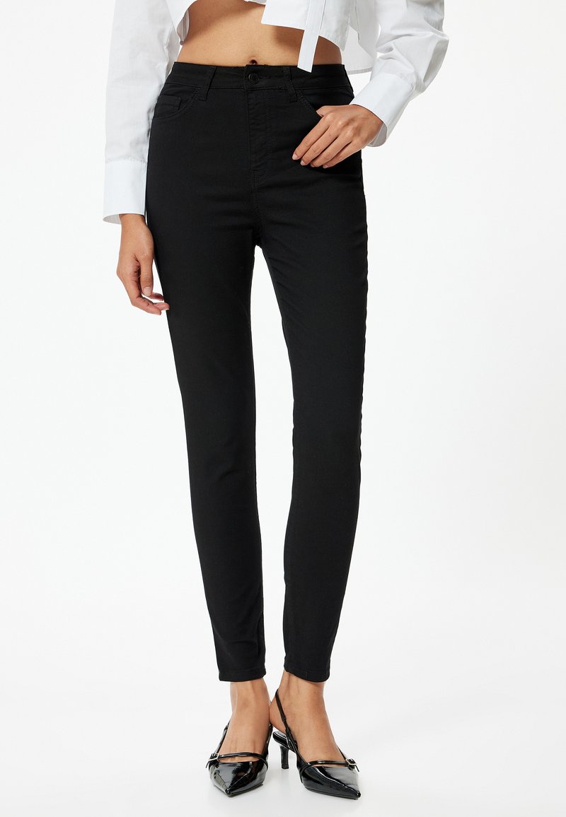 Vaqueros skinny negros hechos de una mezcla de algodón. Presentan un diseño clásico de cinco bolsillos y una cintura de altura media. Textura suave, ajuste hasta el tobillo.
