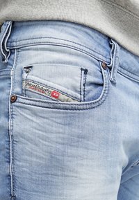 Ljusblå denimjeans med en klassisk femficksdesign, med en synlig logopatch och sömnadsdetaljer på bakfickan.