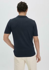 Navy blue short-sleeve polo shirt with a textured knit, featuring a classic collar and a slightly fitted design.