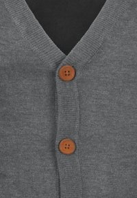 Grå cardigan med V-halsdesign, som har to treknapper og ribbestrikkede kanter for tekstur. Nærbilde viser søm og materiale.