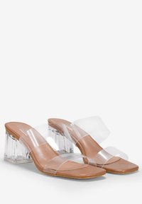 Sandales à talons transparents avec des brides transparentes, semelle intérieure beige et un talon bloc transparent épais. Finition lisse sans embellissements visibles.