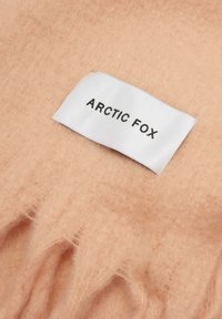 Tissu en laine rose clair avec une douceur au toucher, comportant une étiquette tissée blanche portant l'inscription "ARCTIC FOX" en texte noir.