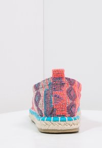 Kolorowe, tkane espadryle z płaską podeszwą, ozdobione czerwonymi, niebieskimi i purpurowymi wzorami, z plecioną podeszwą z jutowej liny i uchwytem z tyłu.