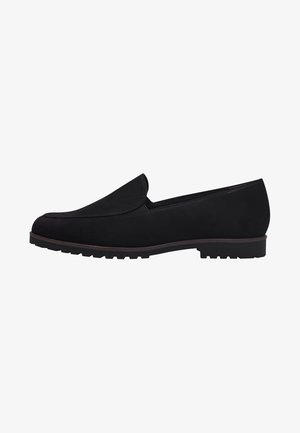 Los mocasines de ante negro presentan una puntera redondeada, un perfil bajo y una suela texturizada con pequeños tacos para tracción. Diseño simple, sin herrajes visibles.