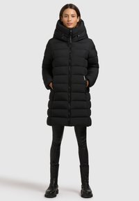 Mustmust värvi puffer-kott, millel on kõrge krae, täispikk lukk ja küljetaskud. Tikitud disain sisaldab horisontaalseid sektsioone isolatsiooni jaoks.