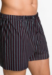 Boxer shorts a righe con una base nera e linee verticali rosse e blu. Vita elastica, dettaglio con bottone e tessuto leggero.