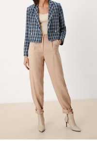 Blå och vit mönstrad kort jacka, beige högmidjade byxor och cremfärgade ankelstövlar med spetsig tå, placerade på en neutral bakgrund.