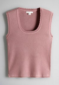 Bezrukávový vrúbkovaný pletený top v prachovej ružovej farbe s vlnitými okrajmi a okrúhlym výstrihom, veľkosť stredná, položený na šedom povrchu.