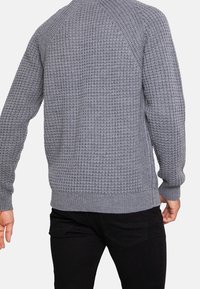 Grijze gebreide trui met een textuurpatroon, geribde manchetten en zoom. Voorzien van een ronde hals en raglanmouwen voor meer bewegingsvrijheid.