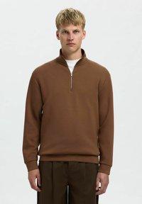 Brauner Sweatshirt mit Viertelreißverschluss und langen Ärmeln, aus weichem Stoff gefertigt. Verfügt über einen silbernen Reißverschluss und sitzt bequem an der Taille.
