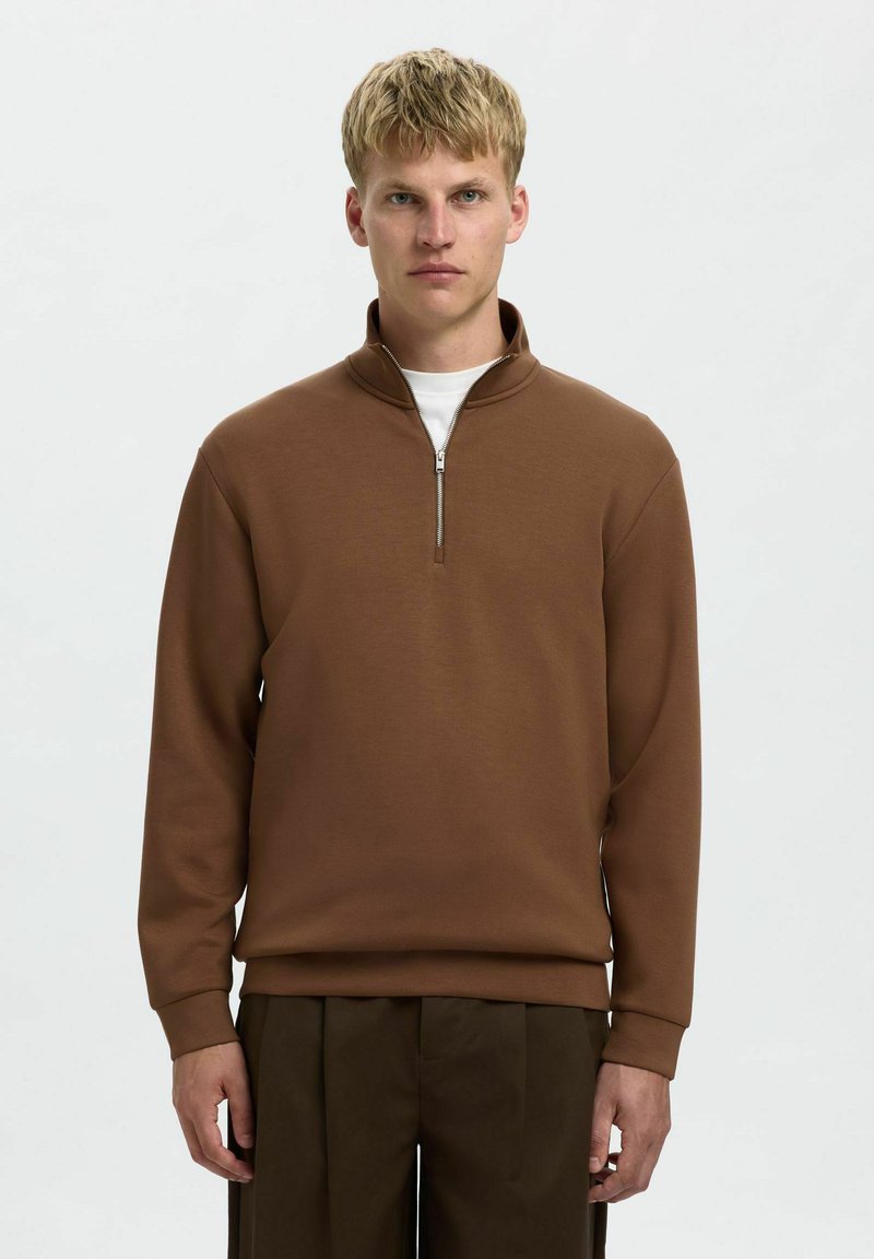 Brauner Sweatshirt mit Viertelreißverschluss und langen Ärmeln, aus weichem Stoff gefertigt. Verfügt über einen silbernen Reißverschluss und sitzt bequem an der Taille.
