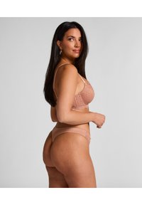 BH en g-string set met kantafwerking in een zachte nude kleur. BH heeft contourpadding en verstelbare bandjes. De g-string heeft delicate kantaccenten.