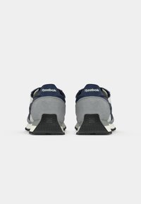 Mornarske i sivo tenisice s glatkom i teksturiranom završnom obradom. Imaju gumeni potplat i Reebok brending na peti.