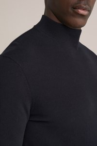 Melns, augsta kakla džemperis no smalki ribota, mīksta auduma; cieši pieguļošs dizains, kas izceļ kaklu un plecus.