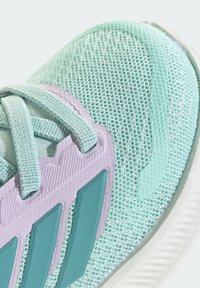 Αθλητικό παπούτσι σε ανοιχτό τιρκουάζ χρώμα με ανώτερο μέρος από διαπνέον πλέγμα, μοβ και τιρκουάζ λεπτομέρειες και υφασμένο καουτσούκ στη σόλα. Διαθέτει ρυθμιζόμενα κορδόνια.