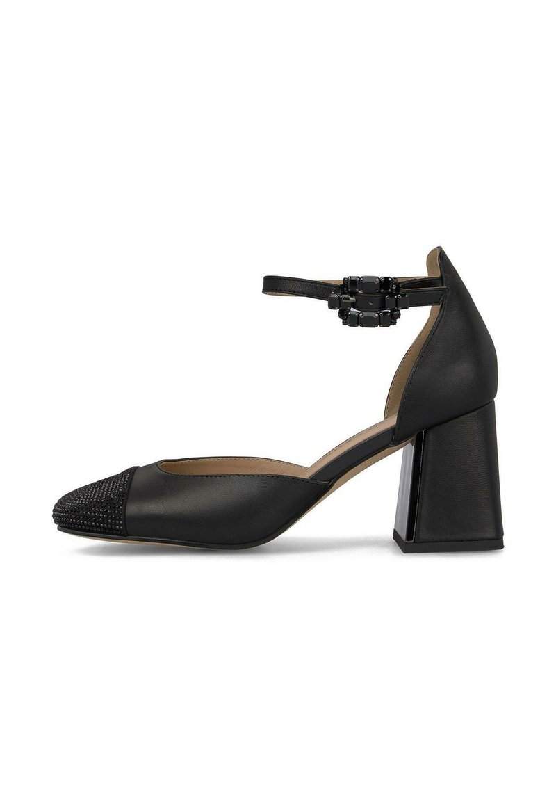 Zapato de tacón negro con correa al tobillo, puntera texturizada con perlitas, tacón block ancho, parte superior de cuero liso y un detalle decorativo de hebilla.