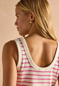 Prúžkovaný top bez rukávov z mäkkého rebrovaného materiálu v krémovej farbe s ružovými horizontálnymi pruhmi a širokým okrúhlym výstrihom.