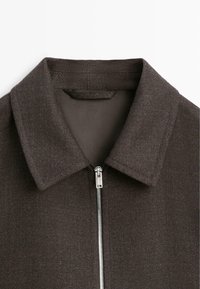 Giacca marrone con zip, colletto, tessuto strutturato e cerniera argentata. Fodera interna in tonalità a contrasto.