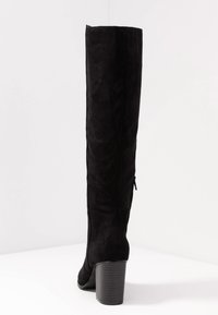 Czarny zamszowy kozak za kolano z obcasem typu blok, o gładkiej fakturze i bocznym zamkiem błyskawicznym dla łatwego zakładania.