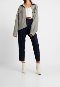 Harma hounds-tooth ylikoko takki, kerma lyhyt toppi, tummansininen ruudullinen korkeavyötäröinen housut ja vaaleanbeiget nilkkurit terävällä kärjellä.