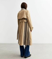 Beige trenchcoat med rutigt foder, dubbla slitsar bak och bälte i midjan. Matchad med vida blå denimbyxor.