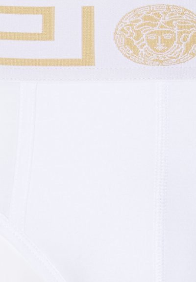 Slip in cotone bianco con vita elastica dorata decorata con un emblema di Medusa e un motivo geometrico. Texture liscia con cuciture a vista.