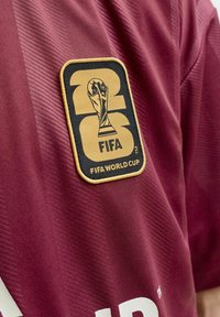 Χρυσή και μαύρη παράσταση FIFA World Cup 2022 σε μπορντό ύφασμα αθλητικής φανέλας με υφή.