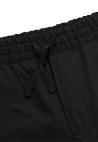 Black shorts with an elastic waistband and drawstring. Features a subtle grid texture and side pockets. Durable fabric for comfort.