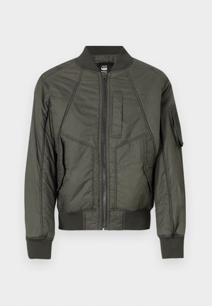 Tume rohelise värvi bomber-jakk, kus on ees lukuga sulgemine, ribakudumisega mansetid ja alus, mitmed taskud ning tekstuuriga, kergelt läikiv viimistlus.