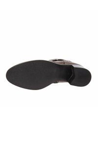 Suela de zapato de cuero marrón con goma negra texturizada. Presenta un ligero tacón y una forma redondeada, diseñada para estabilidad y agarre.