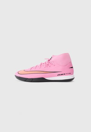 Chaussure de sport montante Nike Air Zoom rose avec semelle noire et logo Swoosh orange sur fond gris clair.