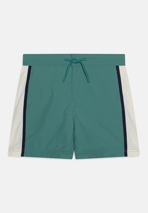 Shorts de bain teal avec une taille à cordon ; présentent des panneaux latéraux blancs avec des accents navy et une texture lisse et légère.
