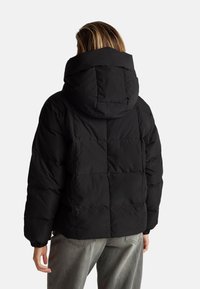 Czarna kurtka puchowa z kapturem, z pikowanym wzorem i elastycznymi mankietami. Miękka tekstura, krótki fason i minimalistyczny styl.