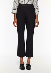 Pantalons noirs à longueur de cheville avec une taille cintrée, en tissu lisse. Le design est ajusté avec une ouverture de jambe évasée.