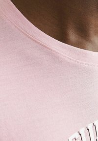 Helles rosa Baumwoll-T-Shirt mit Rundhalsausschnitt und weicher Textur, mit weißem Drucktext auf der Vorderseite.