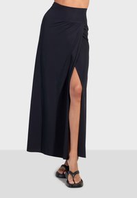 Crna maksi suknja s visokim prorezom, izrađena od mekanog, rastezljivog materijala. Ima široki pojas za udobnost i elegantan, drapiran dizajn.