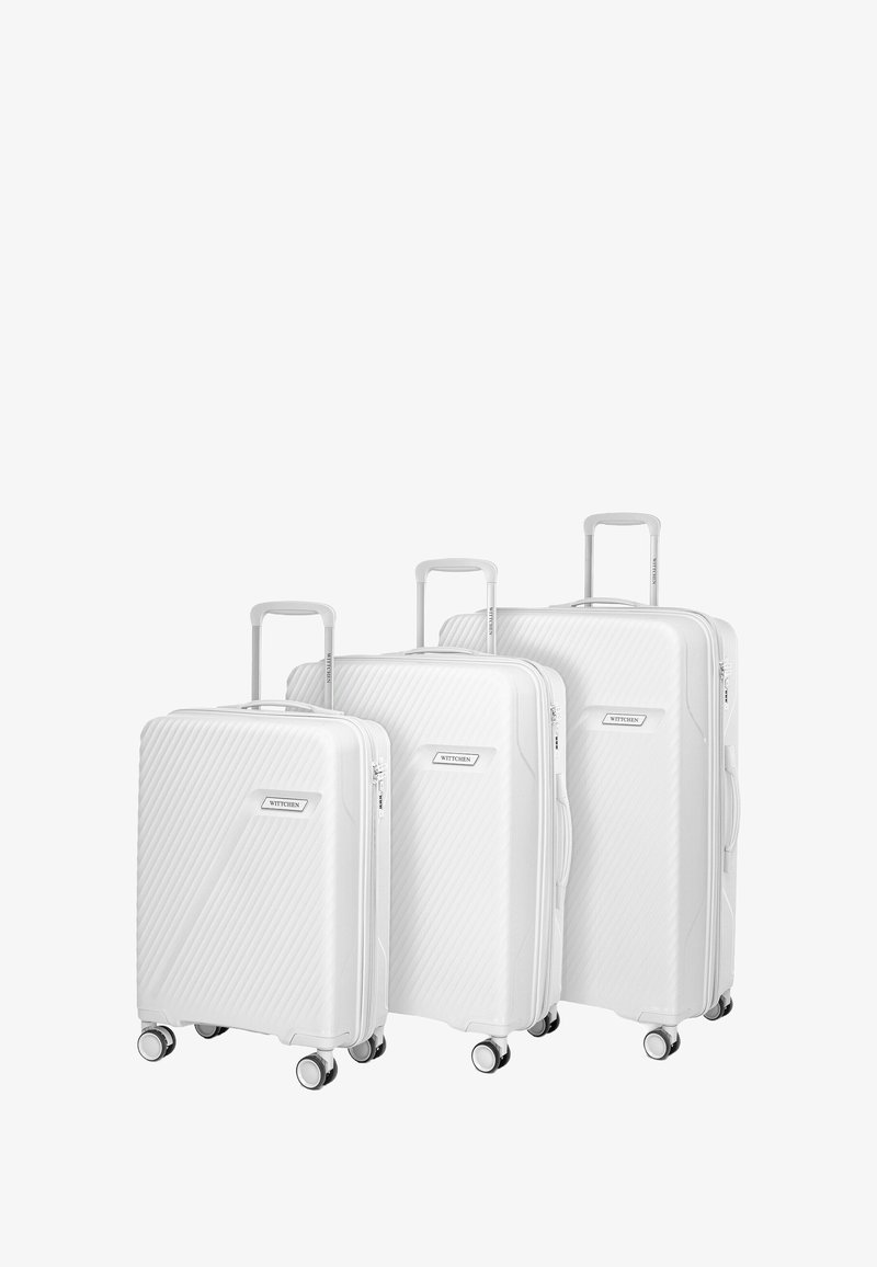 Tre valigie rigide bianche di diverse dimensioni con quattro ruote girevoli e manici telescopici estensibili, disposte affiancate.
