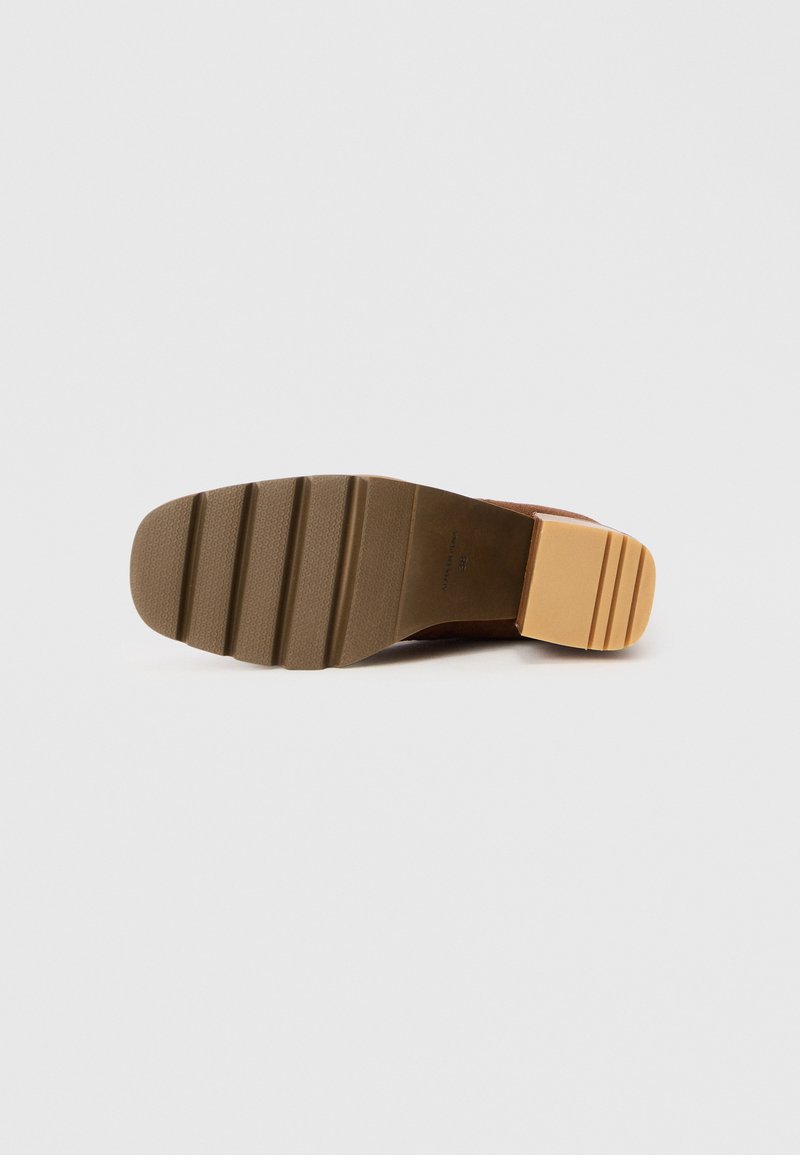 Suela de zapato marrón con una superficie texturizada, que presenta un tacón rectangular en un tono más claro y ranuras de tracción horizontales.