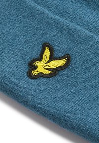 Bonnet tricoté bleu avec une finition texturée, arborant un logo d'oiseau brodé jaune sur le devant, entouré de noir.