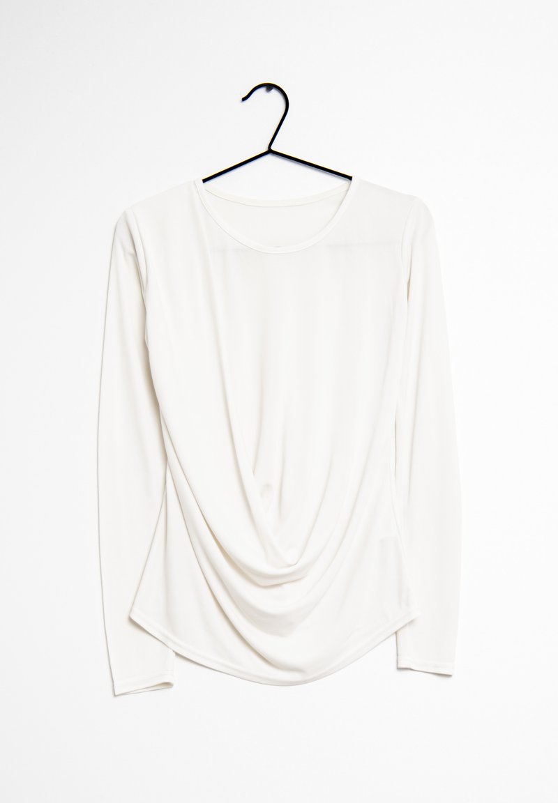 Haut à manches longues drapé en tissu blanc avec un col rond, présentant une texture lisse et des détails de conception subtils le long des côtés.