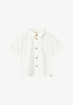 Camisa corta de manga blanca hecha de tejido texturizado. Presenta un cuello puntiagudo, un bolsillo en el pecho y botones de madera en el frente.