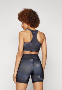Svart sportsbh og shorts-sett med blå geometrisk mønster. Laget av elastisk materiale, med racerback-design og høy midje.
