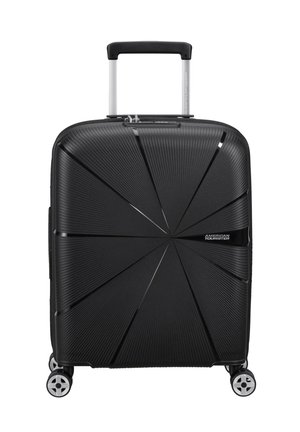 Black hard-shell suitcase with a textured geometric pattern, retractable handle, and four wheels for mobility. Logo positioned on the front.