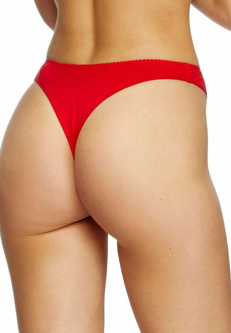 Mujer con braguitas de bikini rojas vista desde atrás, enfocándose en la parte baja de la espalda, caderas y la parte superior de los muslos sobre un fondo blanco.