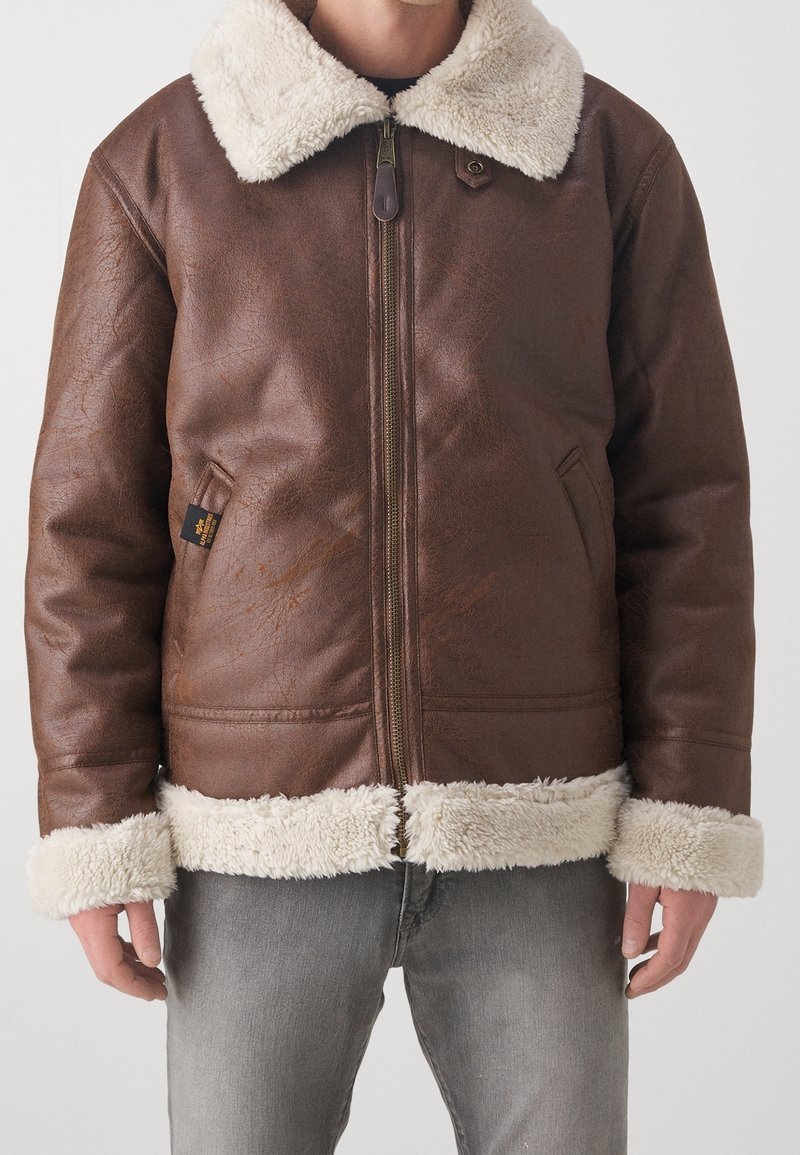 Giacca in pelle marrone con colletto e polsini in pelliccia crema, dotata di una zip frontale e tasche laterali. Finitura texturizzata e design informale.