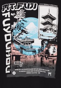 Grafika marškinėliai su juodu pagrindu. Dizainas apima mėlynas ir rožines Mt. Fuji, pagodos, medžių iliustracijas ir japonų tekstą.