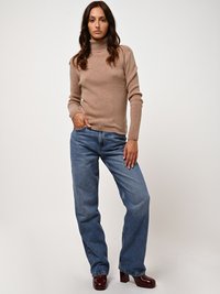 Beige coltrui met geribbelde manchetten, gecombineerd met loszittende blauwe jeans en bordeaux blokhak schoenen. Eenvoudig en casual design.