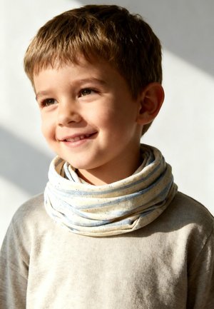 Smiling young boy with short brown hair wearing a light beige shirt and a soft, light-colored scarf around his neck.